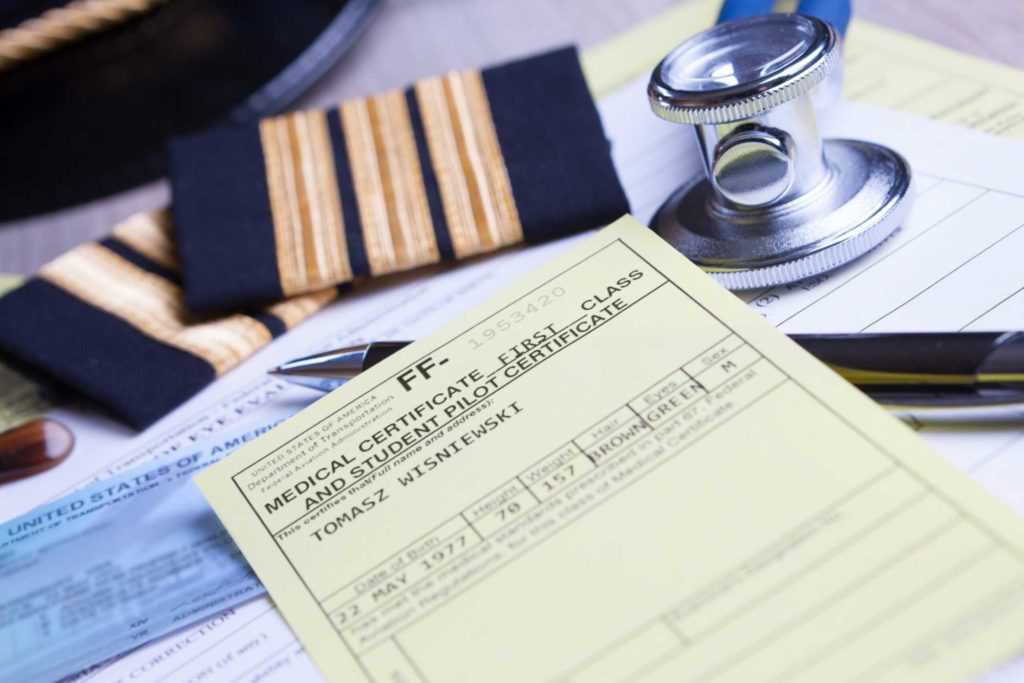 Wisniewska,Monika.Close up of an airline pilot equipment and epaulettes with medical and pilot certificate, stethoscope and pen.Close up shot.FlyingMag