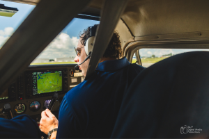 male flight instructor looking out windshield of cessna 172 wearing a headset with the view of the garmin g1000 avionics in the cockpit