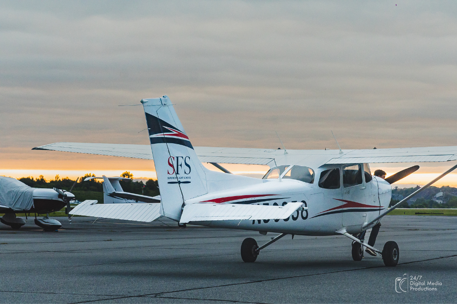 Red white and blue cessna 172 sitting on ramp at sunset