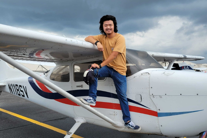 Person standing on the strut of a red, white, and blue Cessna
