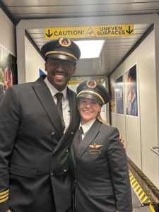 A male and female delta pilot standing in the jetway in uniform