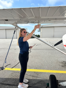 Female instructor sumping the fuel from the wing of a cessna