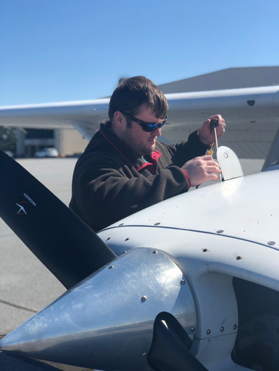 Male flight training student checking the oil in a cessnea